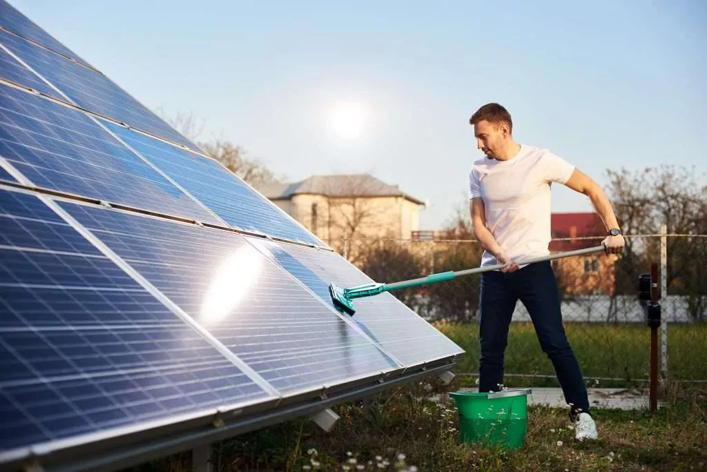 Young man cleaning solar panel